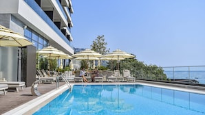 A swimming pool with lounge chairs and umbrellas, overlooking a body of water. - KATAMARE (Becici)