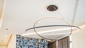 A reception desk with a modern design, a large abstract mural, and a luggage cart. - KATAMARE (Becici)