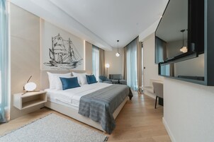 Un dormitorio moderno con una cama grande, mesitas de noche, un escritorio y un espejo amplio.
