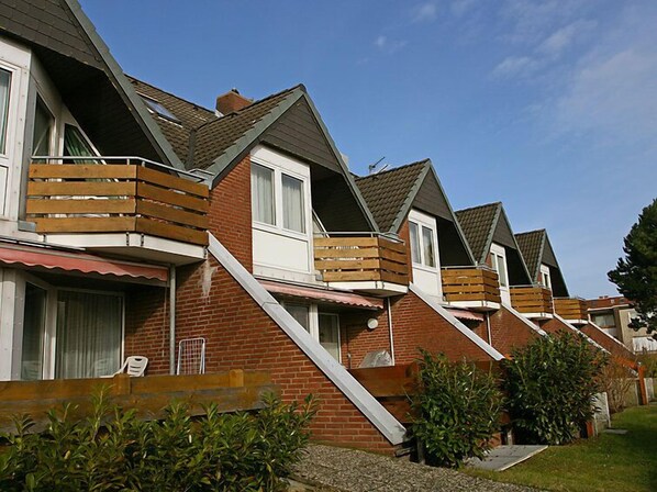 Une rangée de maisons modernes aux façades en briques et aux balcons en bois.