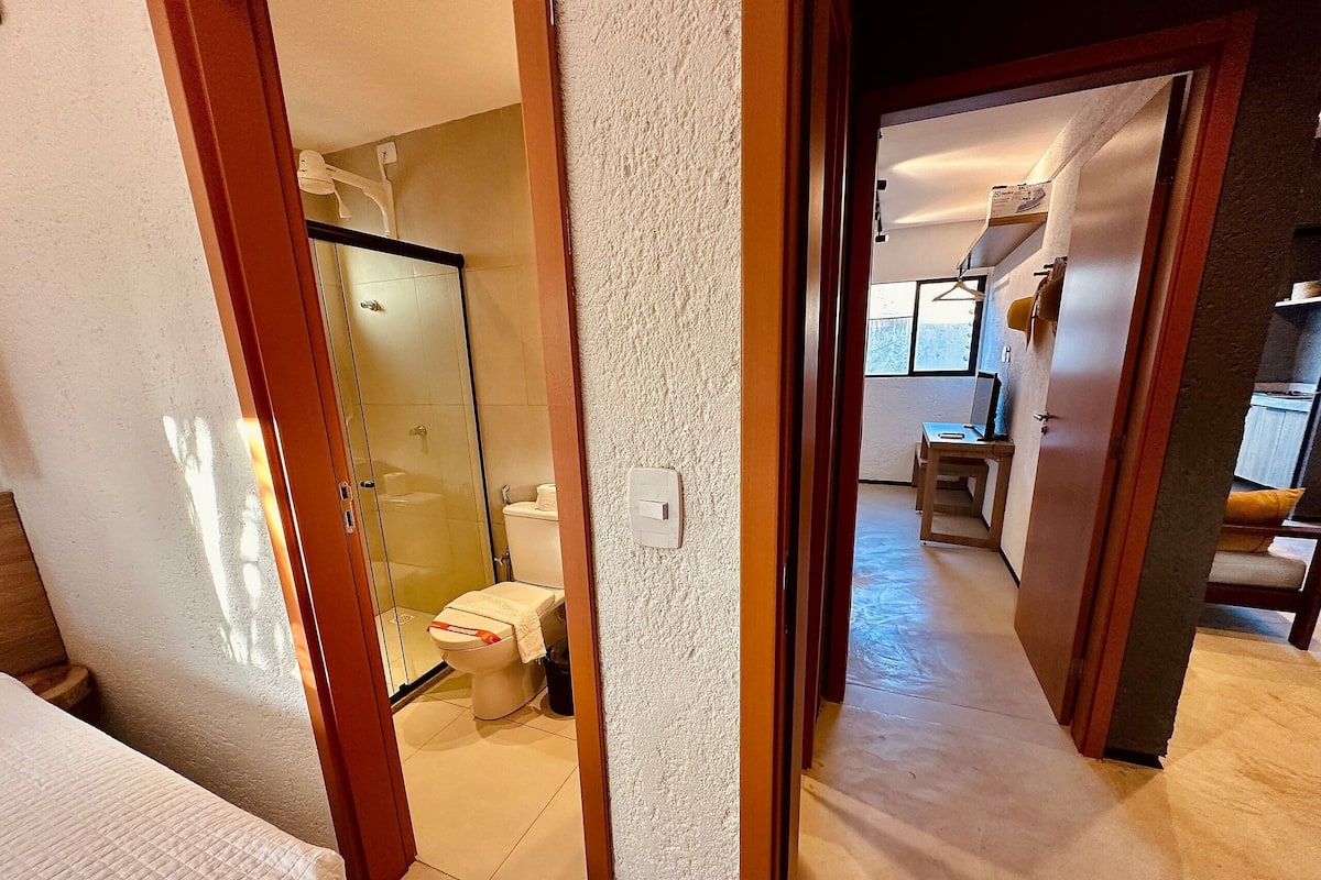 A hotel bathroom with a glass shower enclosure, a toilet, and a sink.