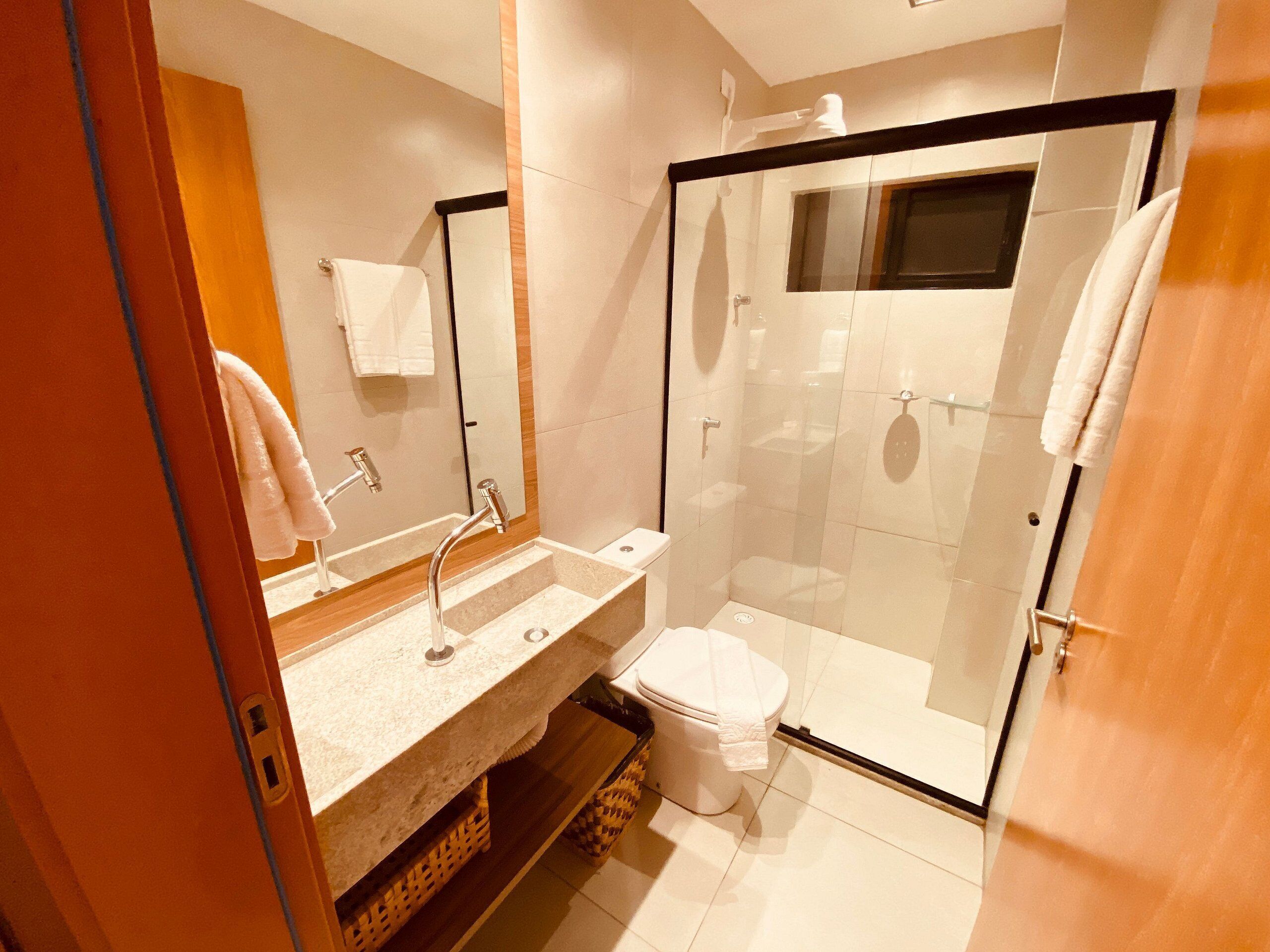 A modern bathroom with a glass-enclosed shower, a sink with a mirror, and a toilet.
