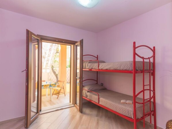 A room with a bunk bed, a sliding glass door leading to a patio with a table and chairs, and a small decorative item on the floor.