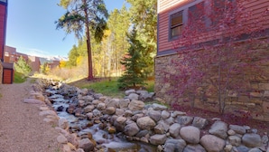 A stream flowing through a rocky bed, surrounded by trees and a building with stone and wooden siding. - Ski-in condo located 1 block from Main St w/ hot tubs, Covered parking, Fantasti (Breckenridge)