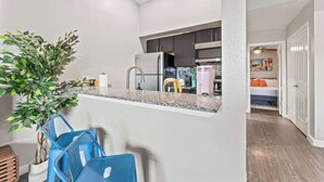 Una cocina moderna con encimeras de granito, electrodomésticos de acero inoxidable y una planta en maceta.