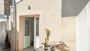 Un patio al aire libre con una mesa dispuesta para dos personas, una botella de champán y un jarrón con flores.