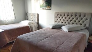 A bedroom with two beds, each with a tufted headboard, and a painting on the wall. - Hotel Pequenino (Canela)