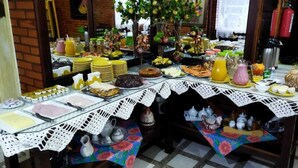 A buffet table with various food items and drinks, surrounded by a white lace table runner. - Hotel Pequenino (Canela)