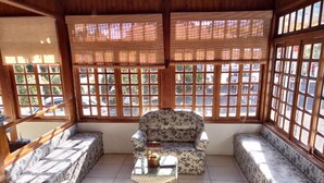A sunlit room with a sofa, two armchairs, and a small table with a vase. - Hotel Pequenino (Canela)
