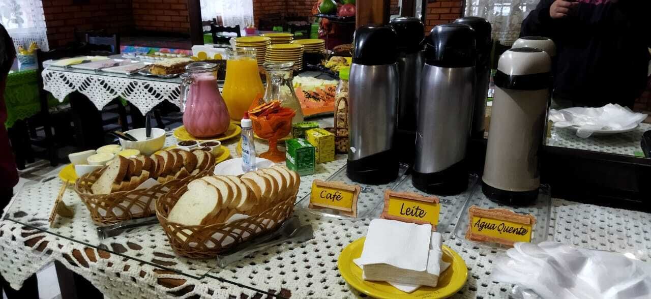 A breakfast buffet with various food items and labeled sections for café, leite, and agua caliente.