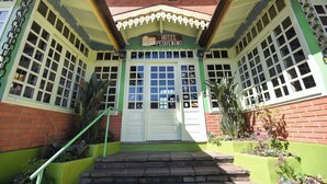 A hotel entrance with a green facade, white doors, and a sign reading "Hotel Pequenino". - Hotel Pequenino (Canela)