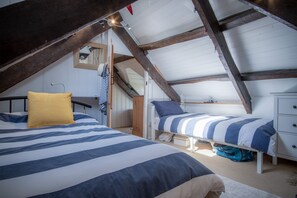 Quarto com duas camas, teto de madeira e parede branca.