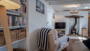 Un salon chaleureux avec une cheminée, un canapé, un téléviseur et des étagères à livres.