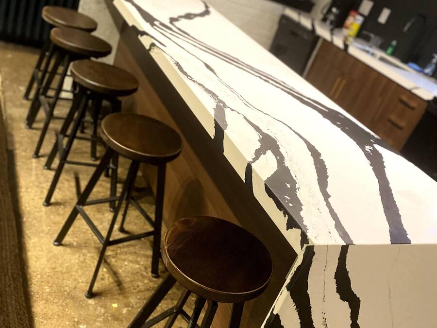 A bar area with a long counter and multiple stools.
