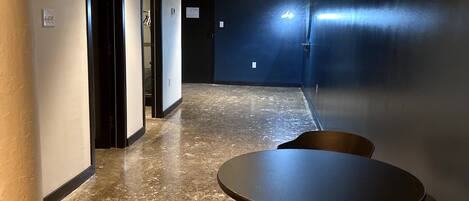 A hallway with a round table and chairs, a door, and a dark wall.