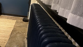 A row of stacked luggage against a wall with a floor lamp and curtains.