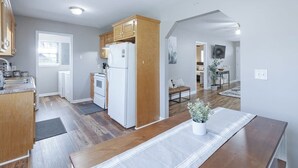 Eine moderne Küche mit Holzausstattung, einem weißen Kühlschrank und einer Essecke mit einer Bank und einem Topf mit Pflanze.