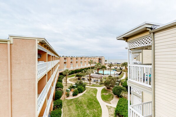 A multi-story hotel with balconies, a swimming pool, and a landscaped garden.