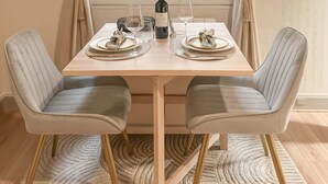 A dining table set for two with a bottle of wine, glasses, and plates. - Lovely studio for 3 in the heart of the Marais (Paris)