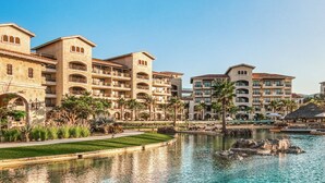 A resort with multiple-story buildings, a central water feature, and palm trees. - Stunning Greg Norman Golfers Paradise with Golf Access (Cabo San Lucas)