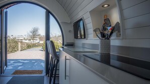 A modern kitchen with a large window, a microwave, and a knife holder on the counter. - Bracken Burrows - 1 Bedroom Pod - New Hedges (Tenby)