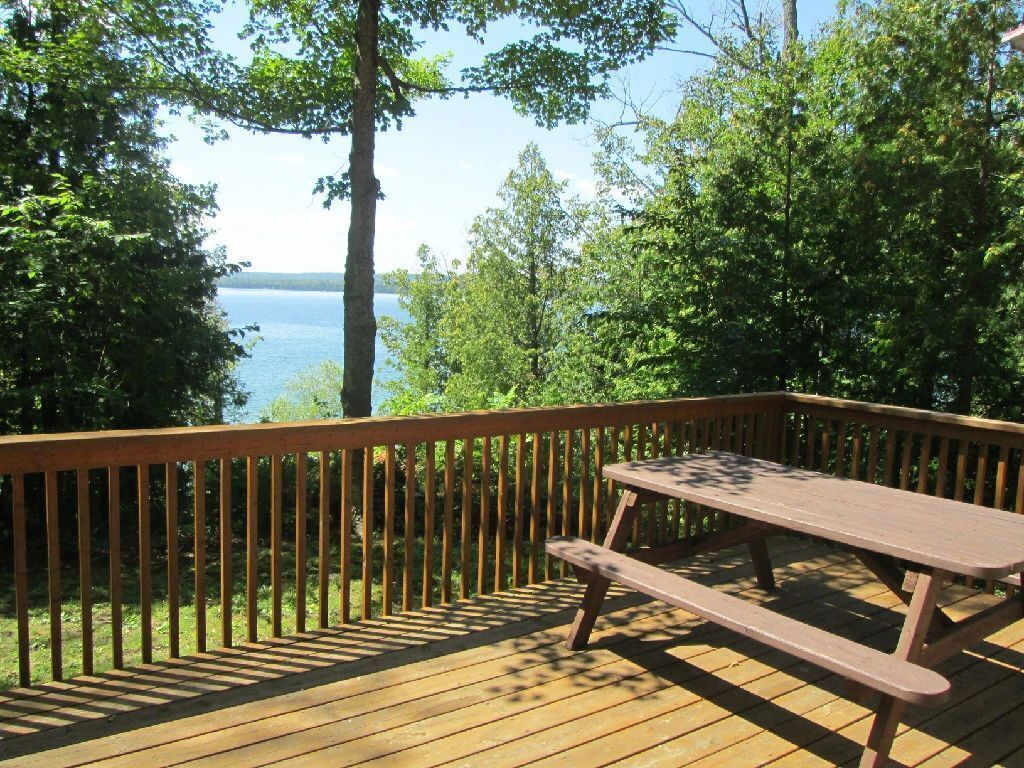 A wooden deck with a picnic table overlooking a lake.