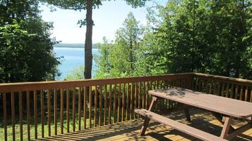 A wooden deck with a picnic table overlooking a lake.