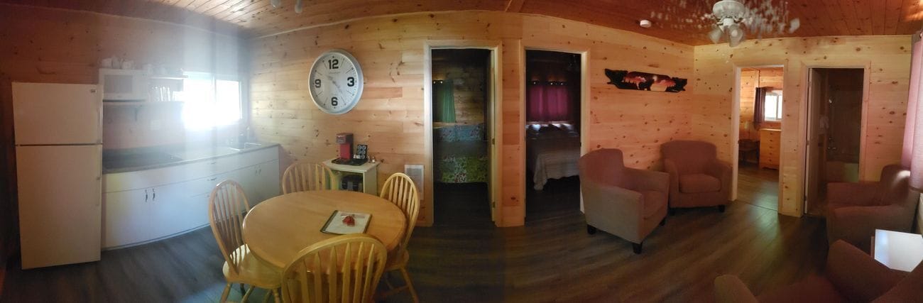 A wooden cabin interior with a kitchen, dining area, and living room.