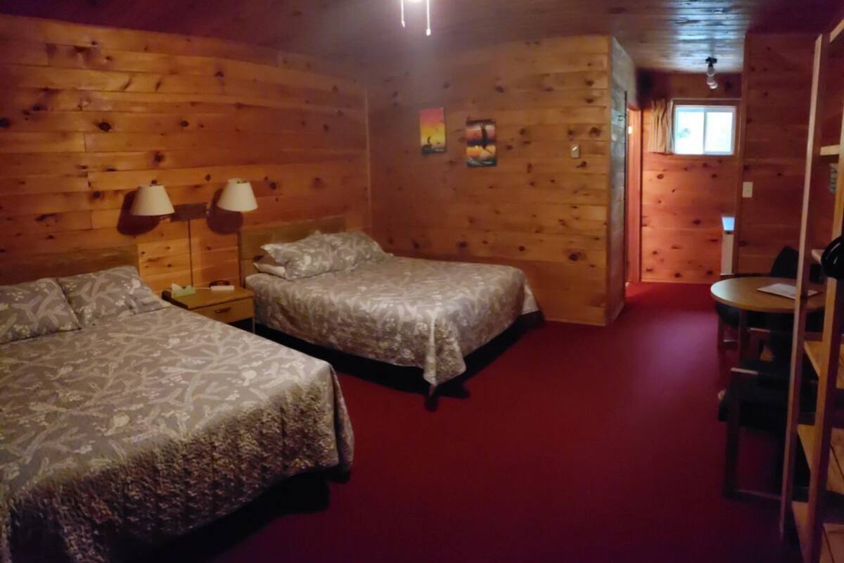Une chambre de style cabane avec deux lits, une petite table et une chaise.