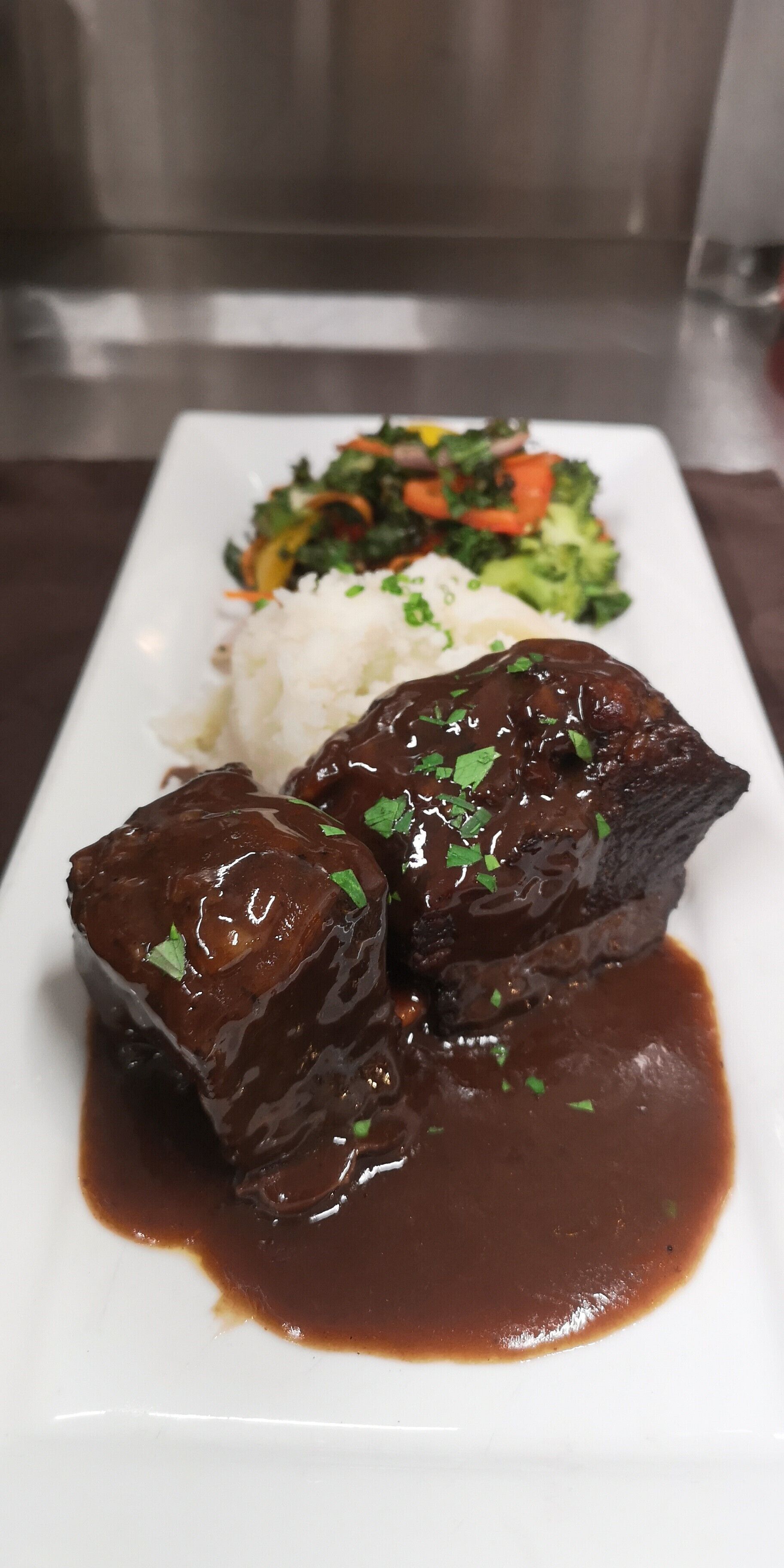 Une assiette comprenant un plat de viande, du riz et un accompagnement de légumes.