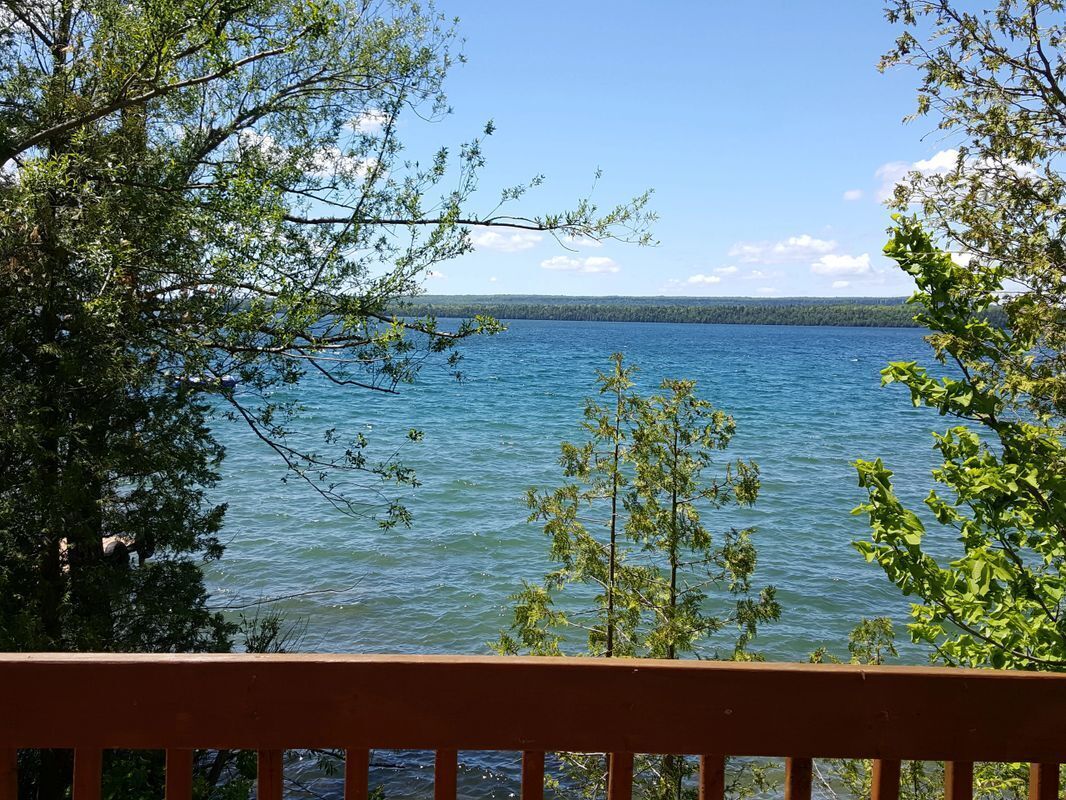 Une vue sur le lac depuis une terrasse en bois, avec des arbres qui encadrent le paysage.