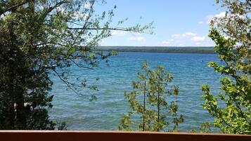 Une vue sur le lac depuis une terrasse en bois, avec des arbres qui encadrent le paysage.
