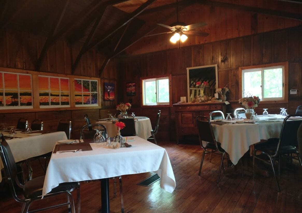 A dining area with wooden walls and ceiling, white tablecloths, and chairs.