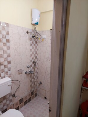 A bathroom with a shower, a toilet, and a hand dryer mounted on the wall.
