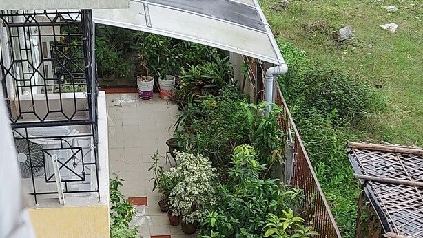 A residential balcony with potted plants, a small table, and a chair. - Serene Peaceful Flat (Kolkata)