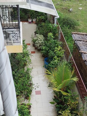 A residential balcony with potted plants, a small table, and a chair.