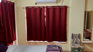 A bedroom with a bed, a chair, a ceiling fan, and an air conditioning unit. - Serene Peaceful Flat (Kolkata)