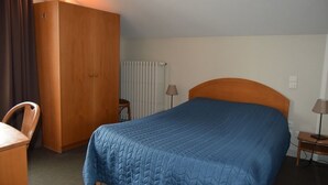 Une chambre d’hôtel avec un lit, une armoire en bois, un bureau et une chaise.