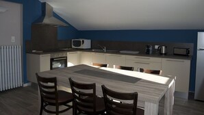Une cuisine moderne dotée d’un îlot central, de meubles blancs, d’un four à micro-ondes encastré et d’une cuisinière.