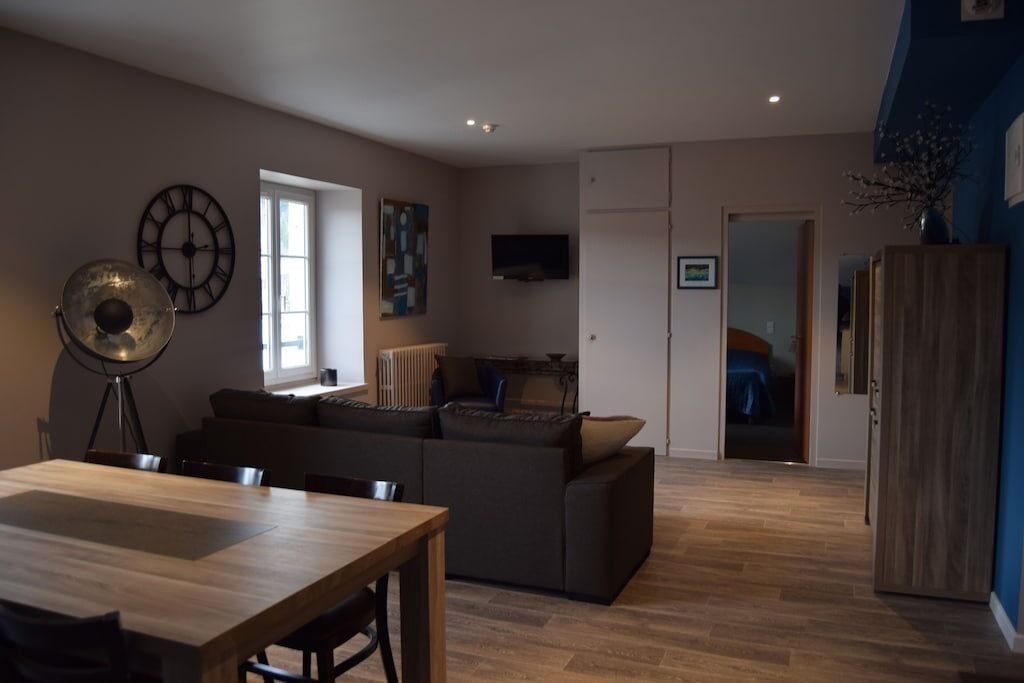 A modern living room with a wooden dining table, a sofa, and a radiator.