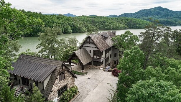 A large, rustic lodge with multiple buildings, surrounded by dense forest and a lake. - Lakewood Pointe and Guesthouse - Free Railroad Admission + Majestic Views + (Bryson City)