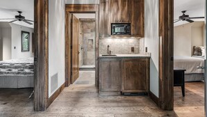 A modern kitchen with wooden cabinets, a microwave, and a tiled backsplash. - Lakewood Pointe and Guesthouse - Free Railroad Admission + Majestic Views + (Bryson City)