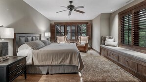 A bedroom with a large bed, a desk, two chairs, a ceiling fan, and a window with blinds. - Lakewood Pointe and Guesthouse - Free Railroad Admission + Majestic Views + (Bryson City)