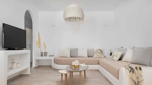 A modern living room with a sectional sofa, a television, a round coffee table, and a hanging light fixture.