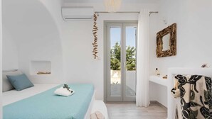 A bedroom with a bed, a bathroom with a sink and mirror, and a view of the outdoors.