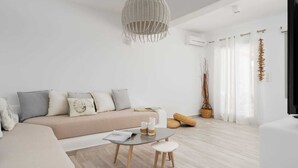 A modern living room with a beige sofa, a glass coffee table, and a hanging woven light fixture.