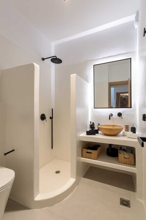 Ein modernes Badezimmer mit Waschbecken, einer Schüssel aus Holz und einem großen Spiegel.