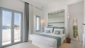 A modern bedroom with a large bed, a view of the sea, and a balcony.
