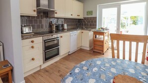 A kitchen with white cabinets, a stove, oven, and a sink. There's a window with a view of greenery outside.