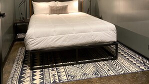 A bedroom with a bed, a nightstand, a TV mounted on the wall, and a patterned rug. - 424 Gold Way - Apt. 404 2Bed/1Bath  (Pittsburgh)